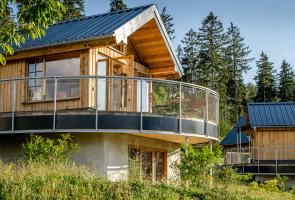 Unsere Nester im Bergdorf LiebesGrün Außenansicht Nest mit einem Balkon mit Wald im Hintergrund