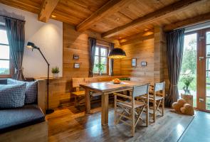 Wohnbereich in Berghütte mit Holztisch und Holzstühlen und Naturblick