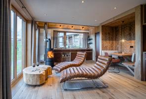 Großzügiger Wonbereich im Bergchalet Lederliegen im Wohnbereich mit Kamin und bodentiefen Fenstern.