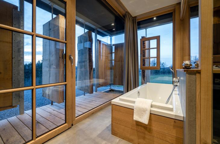Badewanne im Natur-Wellnessbereich mit drehbaren Eichenportalen und in die Natur